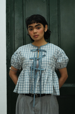 Woman wearing a checkered blouse with a dark background