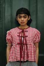 Woman wearing a red and white checkered blouse with a dark background