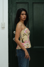 Woman wearing a floral top and jeans standing in front of a dark green door.